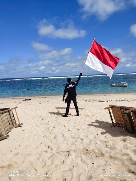 
Anggota komunitas Solidarity Vixion Surabaya (SVS) kibarkan bendera merah putih di Pantai Pandawa Bali