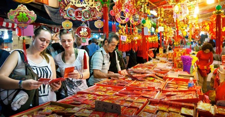 Di jalanan Singapura sudah banyak pedagang jualan pernak pernik Imlek. Tampak bule pun tertarik membeli beberapa suvenir. Foto: Sp/xinhua.