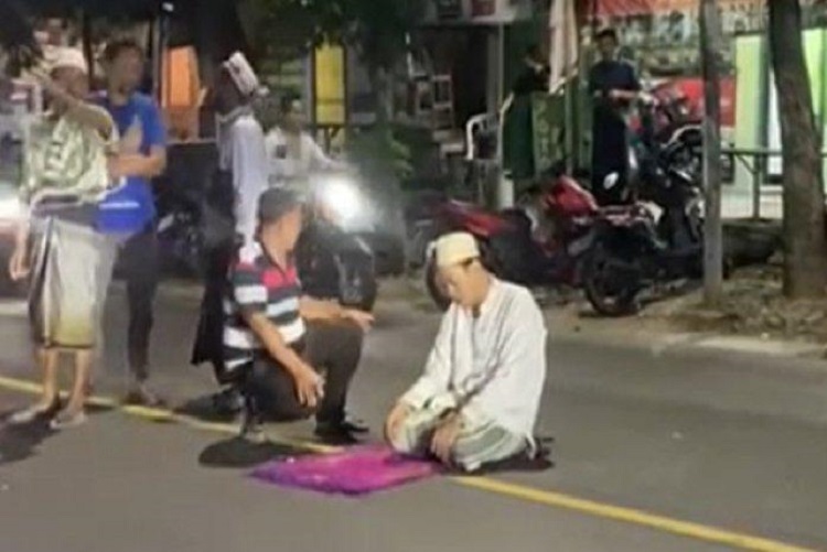 Tangkapan layar sosok pria berbaju koko warna putih shalat di tengah jalan raya Gresik. SP/ GRS